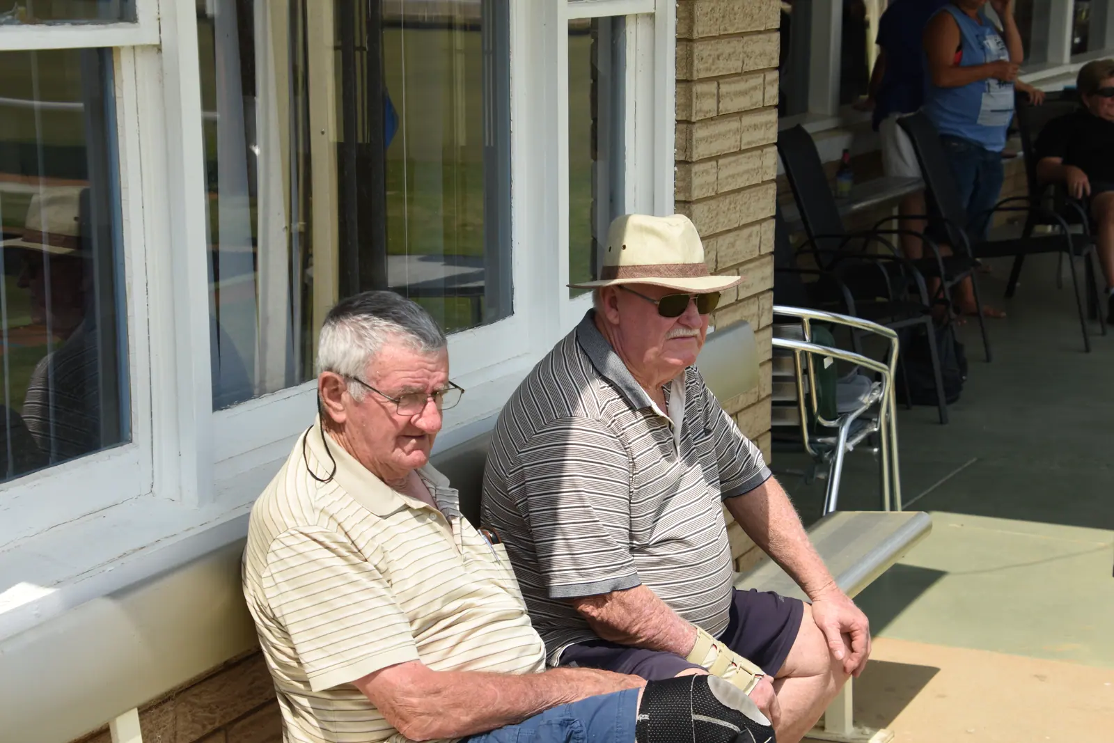 Two members watching play from chairs outside the clubroom