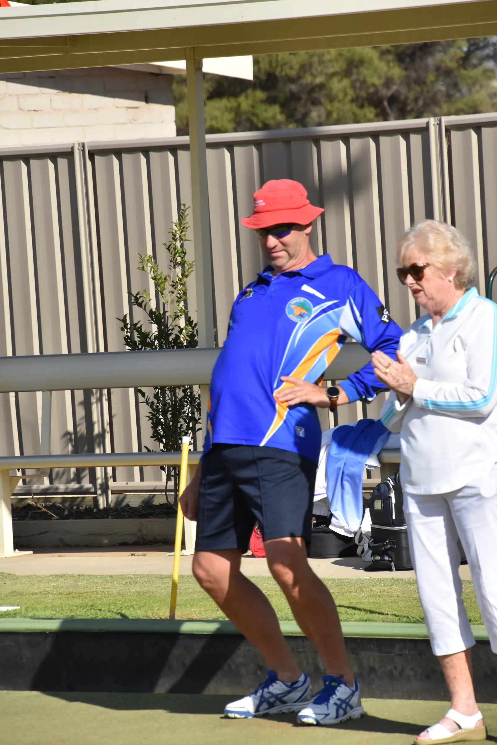 Two bowlers talking tactics between ends beside the green