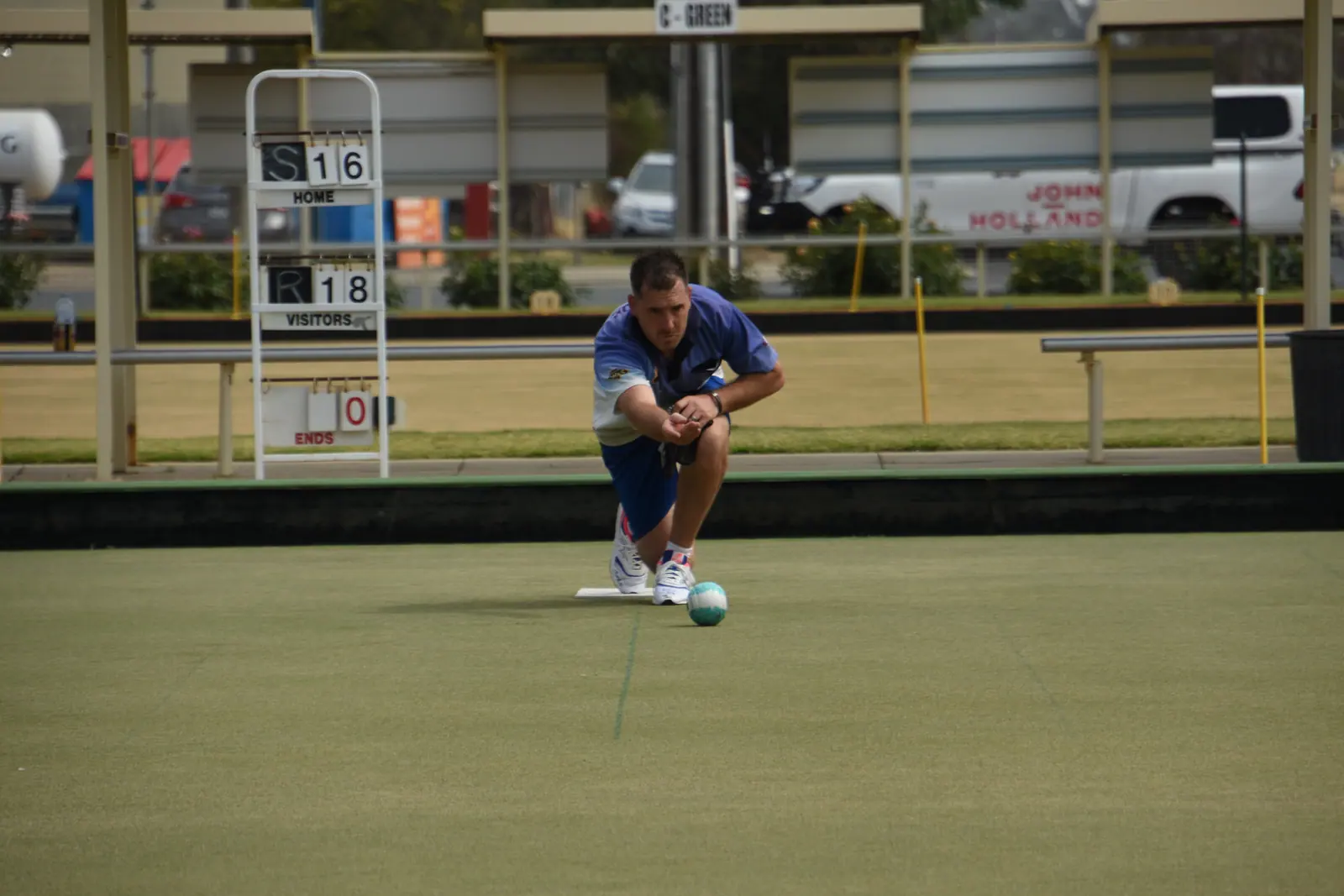 An Echuca Bowls Club member low in the delivery crouch on the championship green
